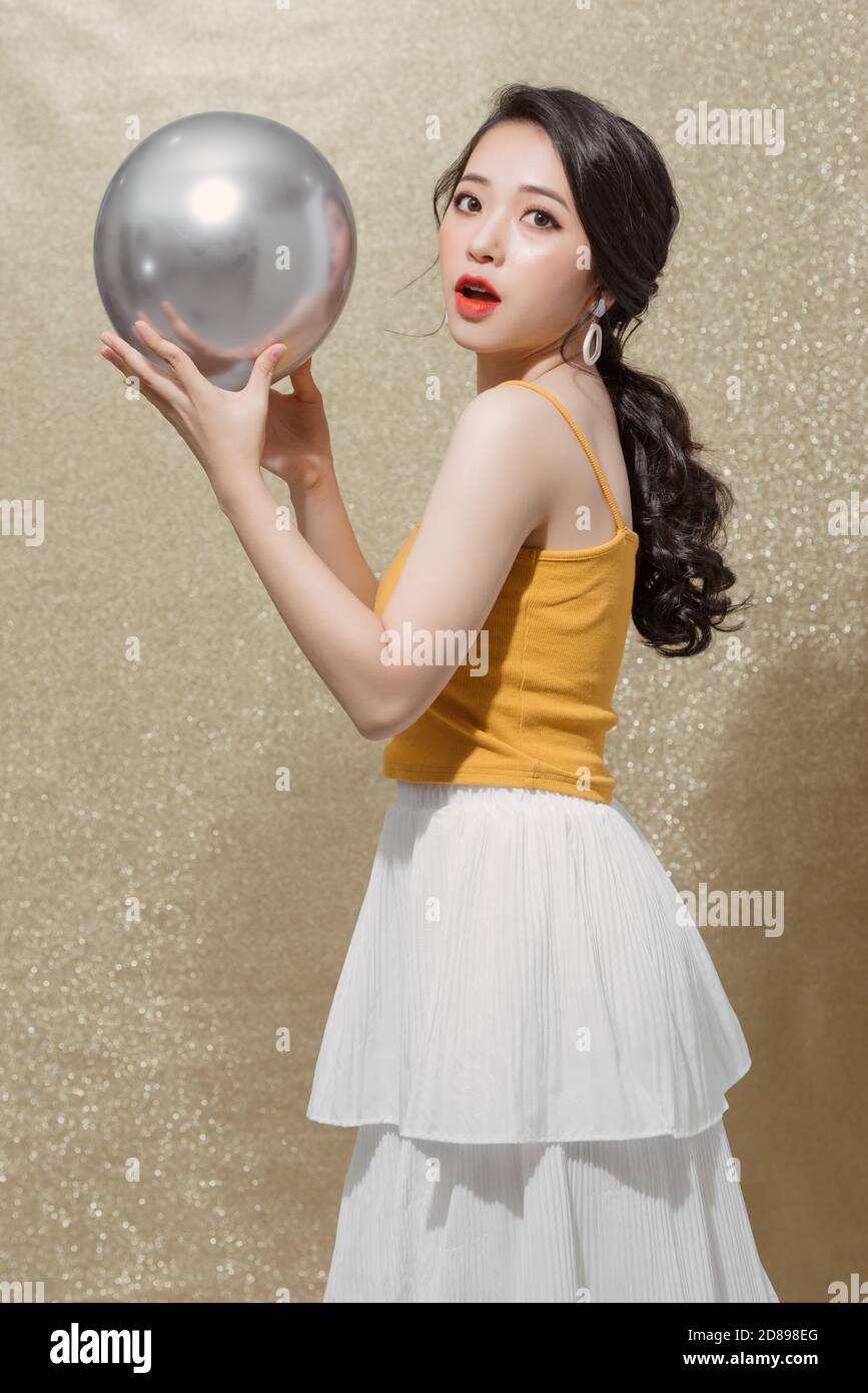 Les jolies jeunes femmes célèbrent l'anniversaire et tiennent des ballons de fête argentés. Banque D'Images