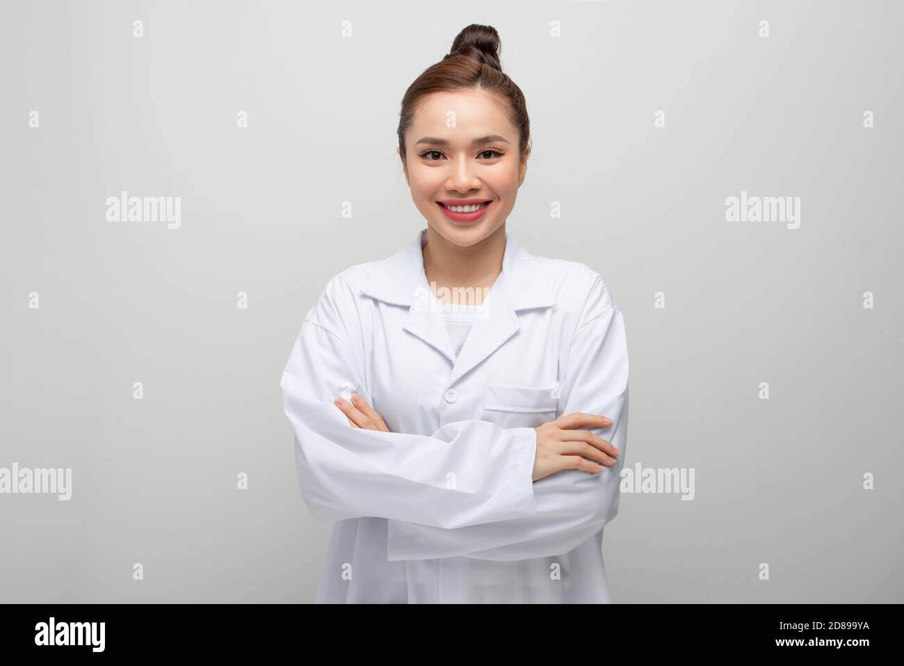 Jeune médecin femme portant un manteau debout sur un fond blanc isolé avec un sourire heureux et frais sur le visage. Banque D'Images