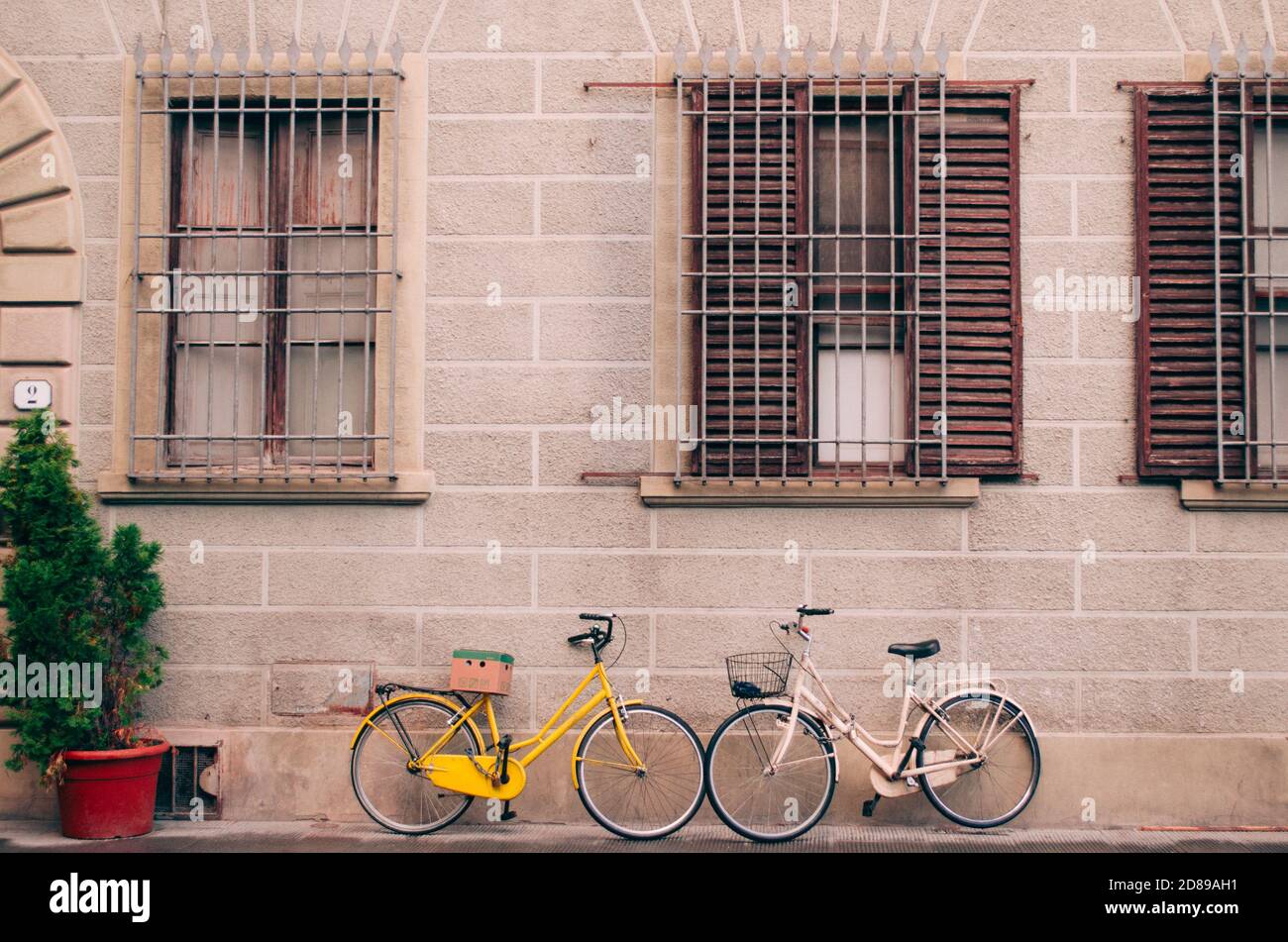 Florence, Italie - deux vélos d'époque garés devant une maison avec des murs en pierre et des fenêtres closes. Banque D'Images