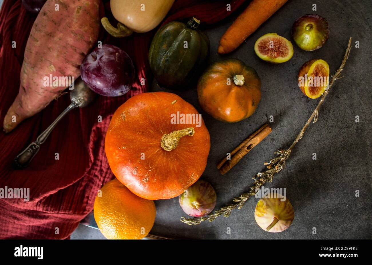 Légumes frais d'automne sur table grise. Vue de dessus photo de noyer cendré, courge, citrouille, carotte, patate douce, oignon, oranges et persil. Récolte d'automne. Banque D'Images