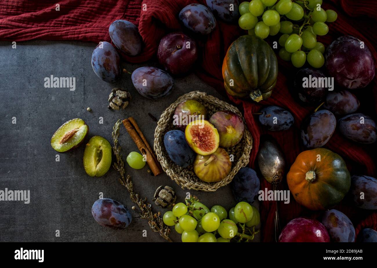 Encore la vie avec des fruits et des légumes frais sur table gris foncé. Vue de dessus photo de pierres précieuses, de raisins, de prunes, serviette de cuisine texturée rouge. Banque D'Images