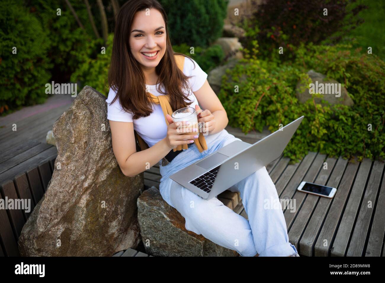 bonne femme indépendante sur pause-café se reposant à l'extérieur assis sur un banc Banque D'Images