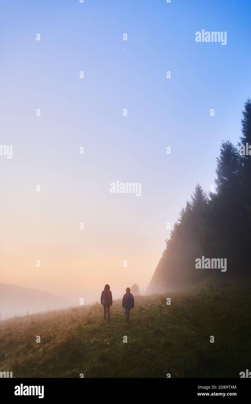 Deux enfants se promo un matin brumeux parmi les arbres. Vue sur les collines de Beskid en Pologne. Banque D'Images