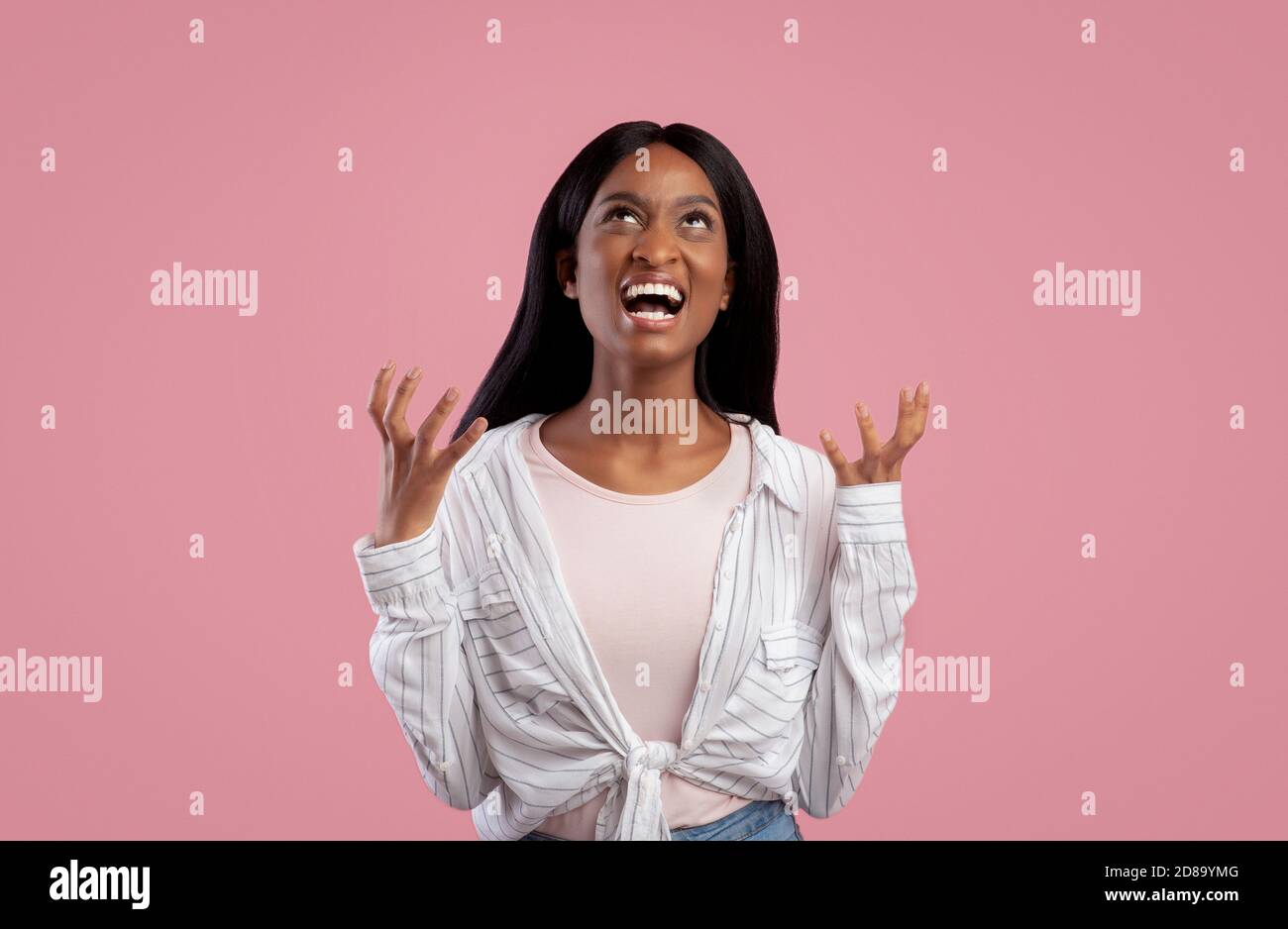 Portrait d'une jeune femme noire en colère hurlant dans un studio rose arrière-plan Banque D'Images