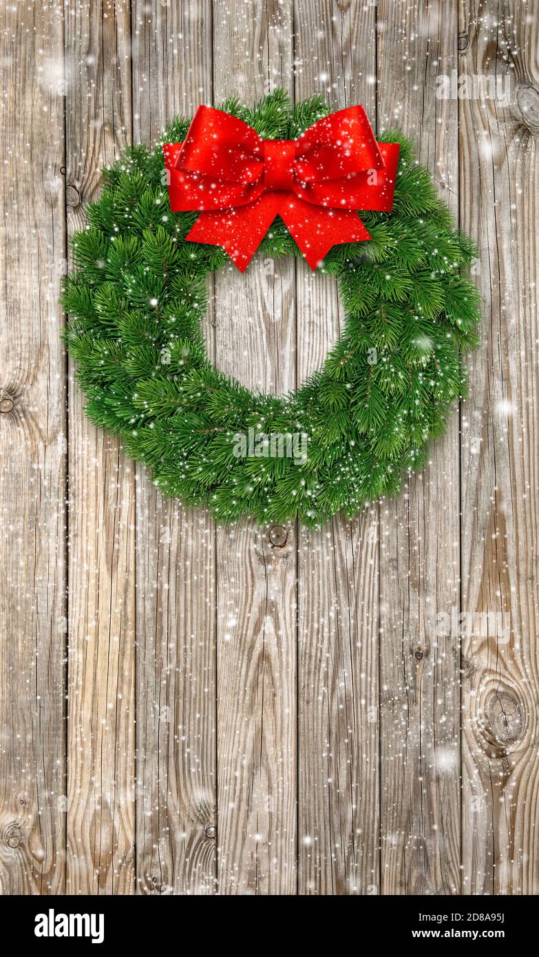 Couronne de Noël avec noeud en ruban rouge et effet neige tombant Banque D'Images