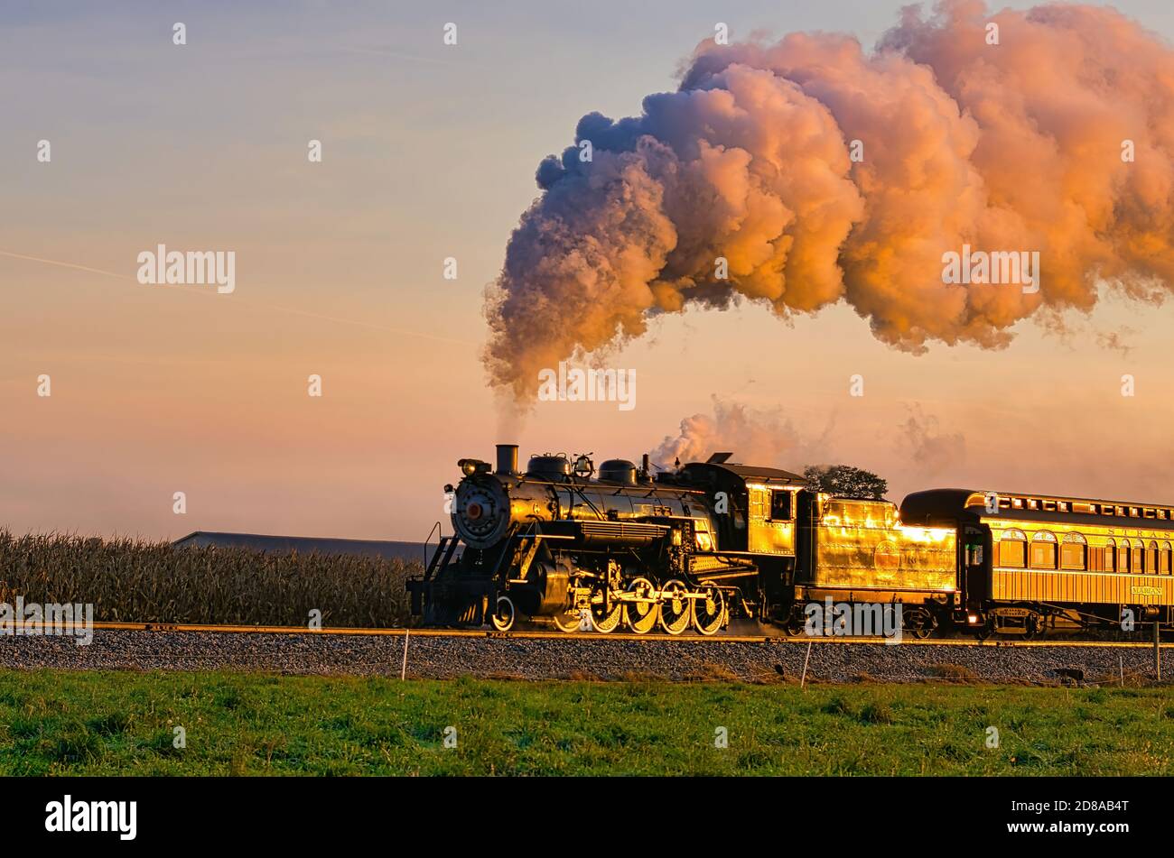 Vue sur le train de passagers Golden Steam au Sunrise Voyager par Campagne Amish avec beaucoup de fumée et de vapeur Banque D'Images