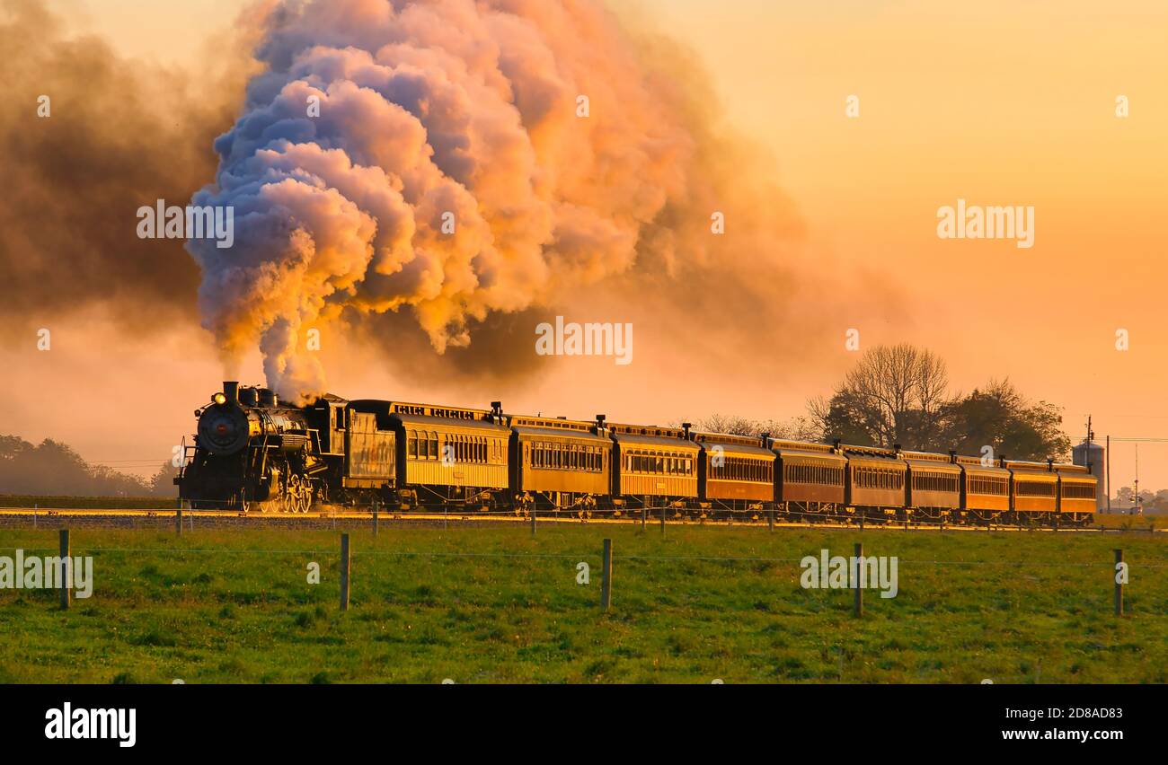 Strasburg, Pennsylvanie, octobre 2020 - vue sur le train de passagers Golden Steam à Sunrise en traversant la campagne amish avec beaucoup de fumée et de vapeur Banque D'Images