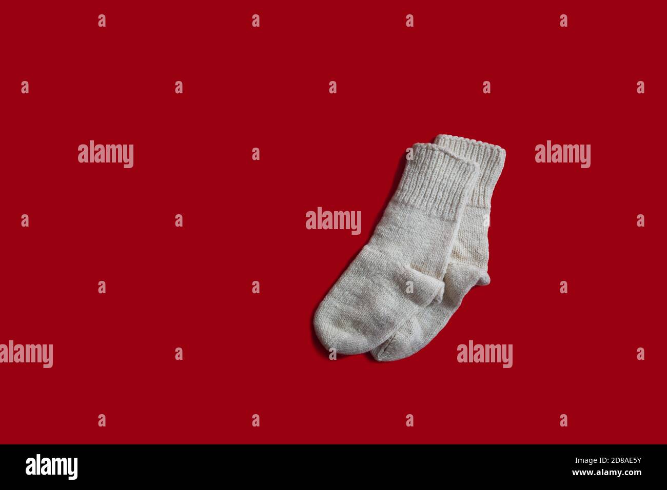 Chaussettes tissées bulgares traditionnelles faites à la main par un grand-mère ancien, isolées sur fond rouge. Chaussettes en laine pour noël hiver froid Banque D'Images