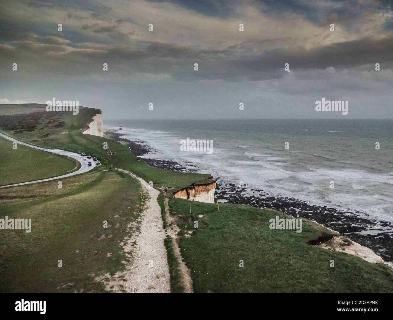 Eastbourne, East Sussex, Royaume-Uni. 28 octobre 2020. Ciel sombre et pluie torrentielle sur les falaises de craie. Phare de Beachy Head au loin. Tandis que l'érosion augmente à mesure que la craie adoucit, ce gros morceau est encore suspendu. Le public est à nouveau averti de la fragilité extrême des falaises avec un risque accru de chute soudaine de roche. Le photographe a utilisé l'équipement approprié et n'était pas près du bord. Crédit : David Burr/Alay Live News Banque D'Images