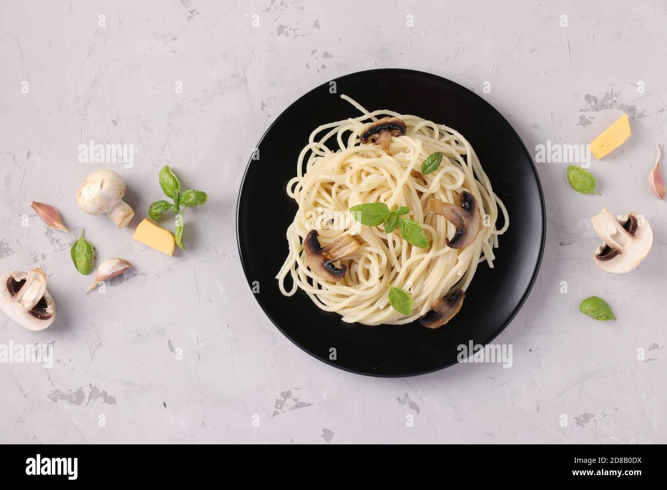 Spaghetti aux champignons et basilic sur plaque noire sur fond gris, vue de dessus, format horizontal Banque D'Images