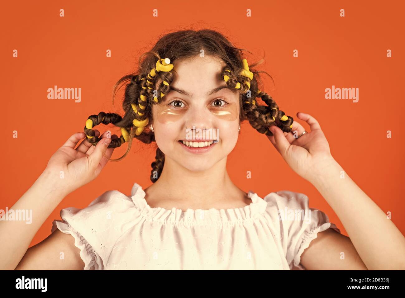 regardez ça. posez avec des cheveux en curlers. bonne fille dans cheveux en curlers jouant salon de coiffure. Conseils faciles pour la coiffure des enfants. Outils de coiffure et accessoires de cheveux. Enfant avec des patches sur le visage. Banque D'Images