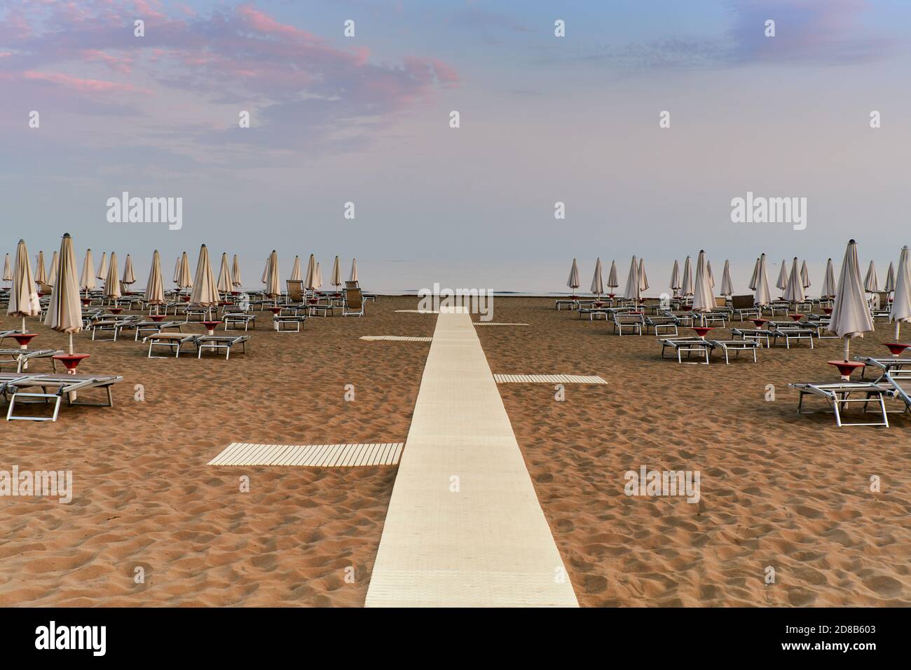 Les chaises longues et parasols sont fermés dans la plage déserte à la fin de la saison estivale à Caorle, la petite Venise. Banque D'Images