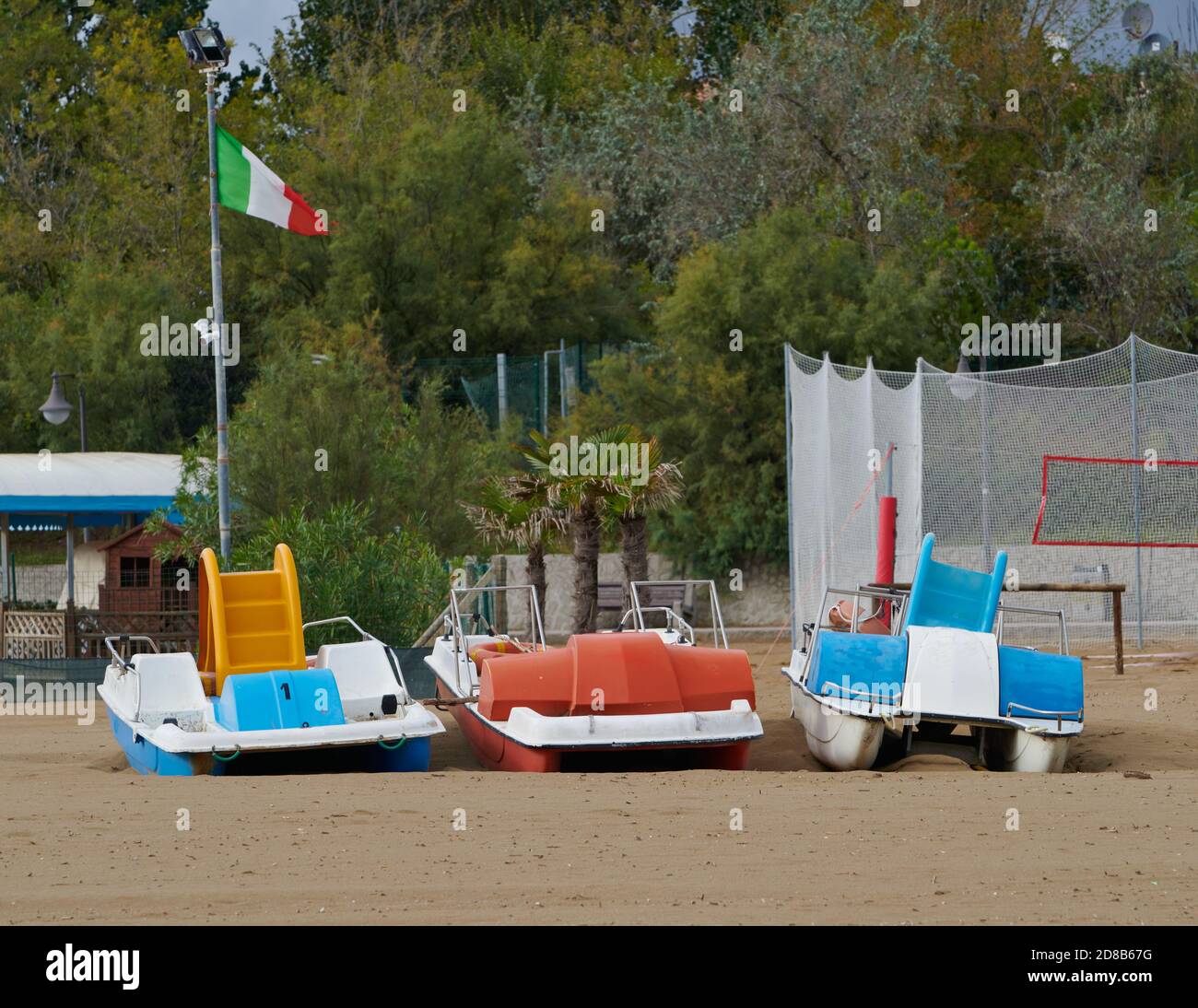 Trois bateaux à aubes avec drapeau italien sur une plage vide à Caorle, Venise, Italie, à la fin de la saison estivale. Banque D'Images