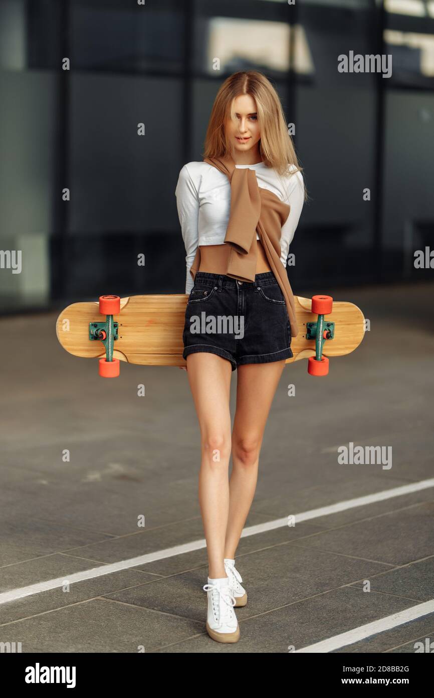 Belle blonde avec un skate dans ses mains. Banque D'Images