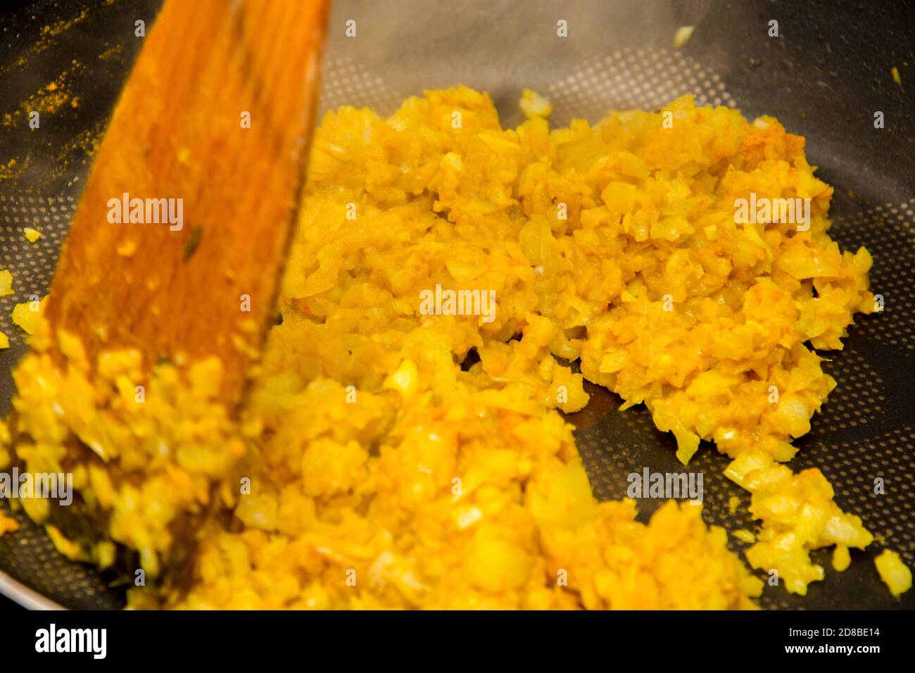 Gros plan sur le mélange de l'oignon frit avec du curry jaune la casserole noire chaude Banque D'Images