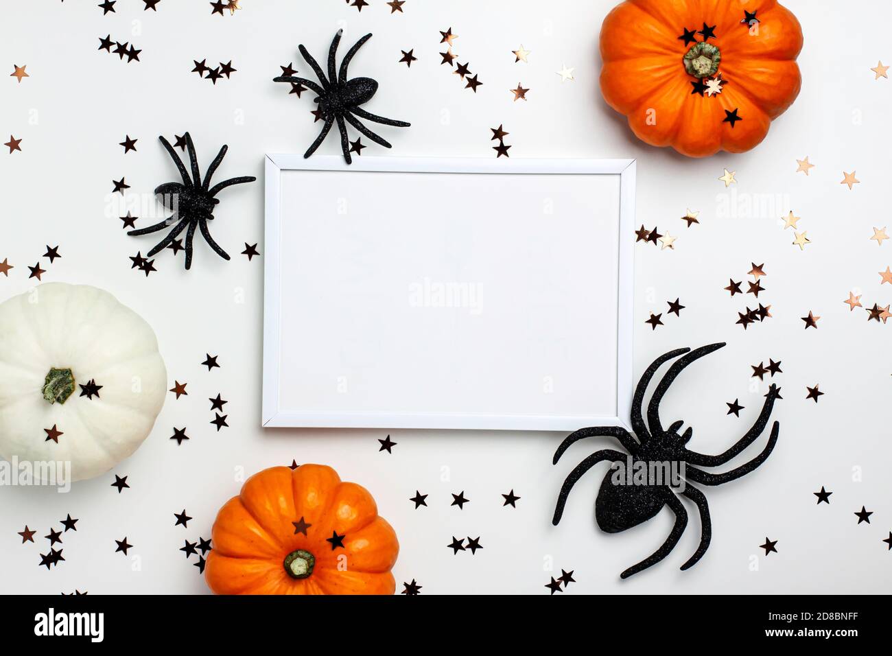 Maquette de pose plate de mini-potiron décoratif blanc et orange, araignées noires et étoiles sur un fond clair d'en haut. Fête d'Halloween et de Thanksgiving Banque D'Images