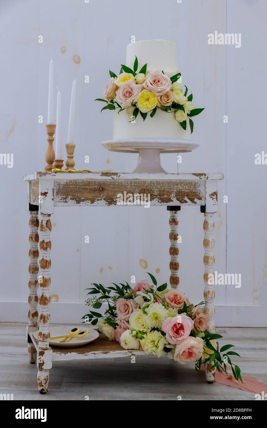 Gâteau de mariage de style rustique avec fleur fraîche et bougies sur table vintage. Banque D'Images