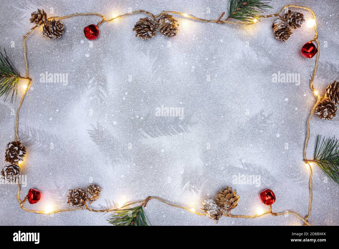 fond de noël avec cadre de guirlande lumineuse décorée de pin cônes et cloches de jingle Banque D'Images