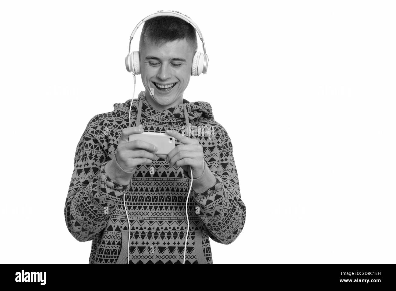 Jeune homme caucasien heureux souriant en jouant avec le téléphone portable et écouter de la musique Banque D'Images Jeune homme caucasien heureux souriant en jouant avec le téléphone portable et écouter de la musique Banque D'Images