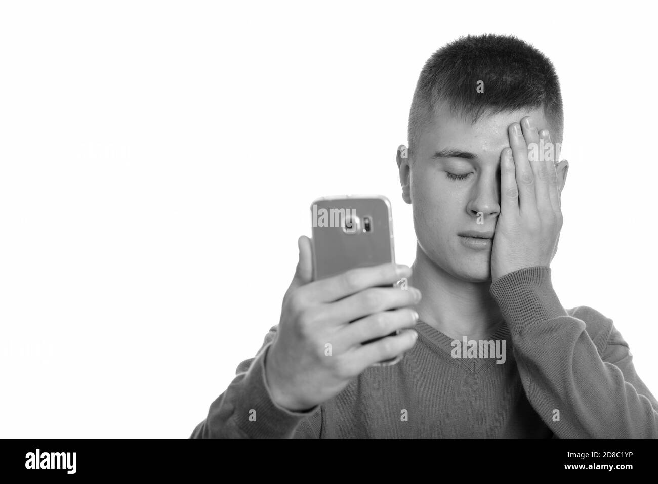 Young Caucasian man holding mobile phone à la fatigue les yeux fermés Banque D'Images