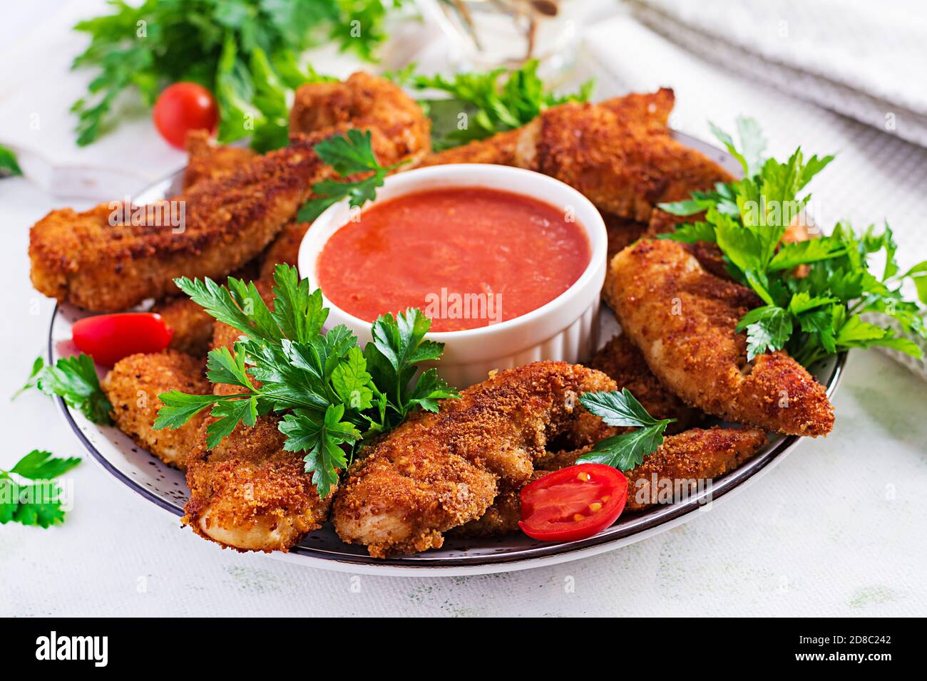 Mini-filets de poulet panés servis avec de la sauce tomate. Cuisine américaine. Nuggets de poulet avec persil. Banque D'Images