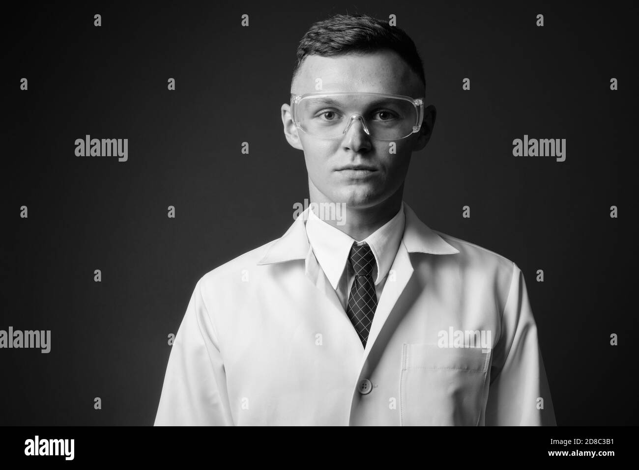 Jeune homme médecin portant des lunettes de protection sur fond gris Banque D'Images