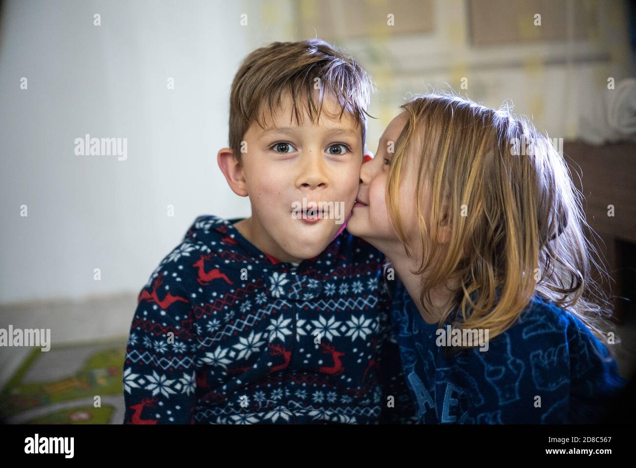 Deux frères et sœurs en pyjama avec livre, soeur baiser frère, drôle émotions énorme maison Banque D'Images