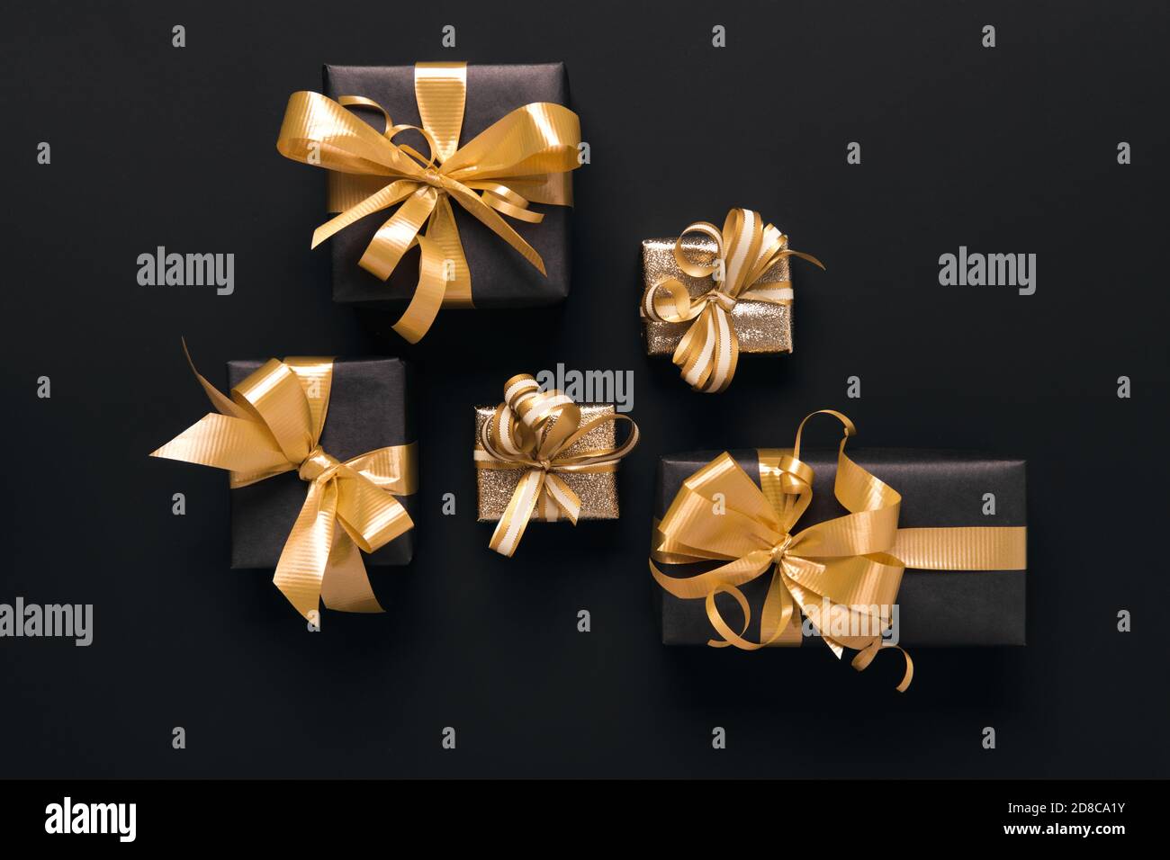 Boîtes-cadeaux dorées emballées de façon festive sur fond noir. Style de pose à plat. Concept des fêtes et du Vendredi fou Banque D'Images