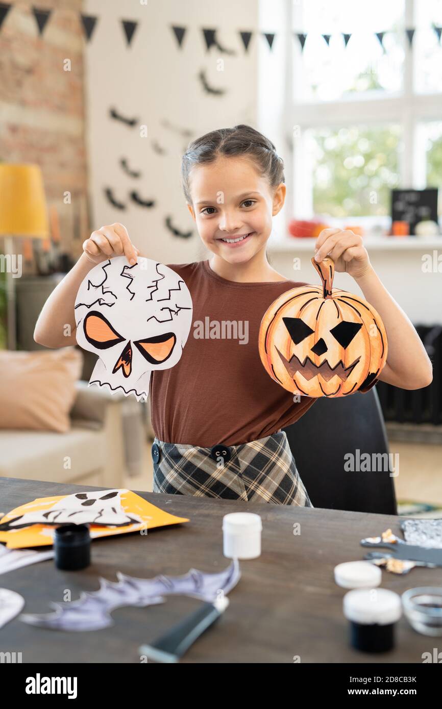 Portrait de gaie brune fille debout avec des décorations d'Halloween à table pleine de fournitures d'art et d'artisanat dans le studio d'art Banque D'Images