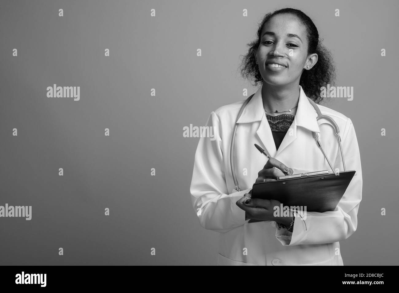 Belle jeune femme africaine médecin contre l'arrière-plan gris Banque D'Images