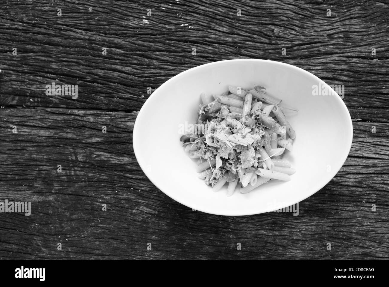 Penne pâtes au thon et tomates fraîches contre une table en bois Banque D'Images