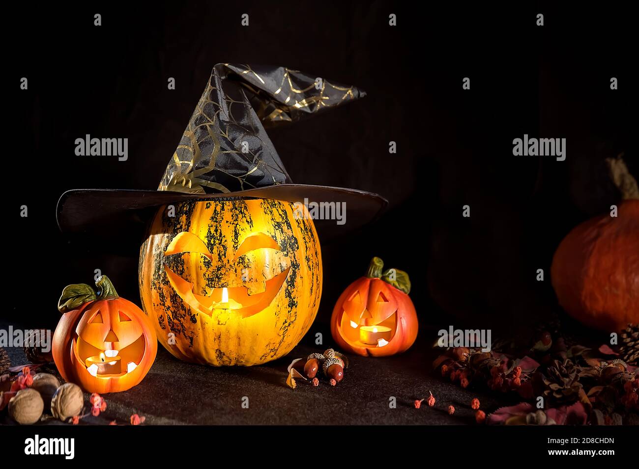 Citrouilles sculptées pour Halloween, la tête de Jack est sur la table. Citrouille dans un chapeau de sorcière. Arrière-plan sombre. Banque D'Images