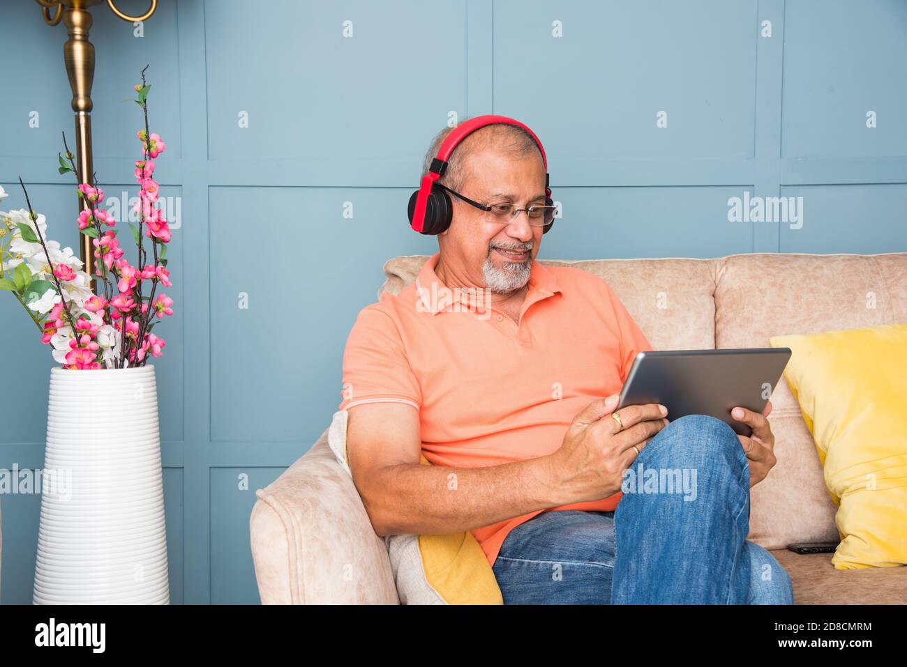 Vieil homme asiatique indien utilisant un casque tout en écoutant de la musique ou regarder des films sur une tablette ou un smartphone Banque D'Images