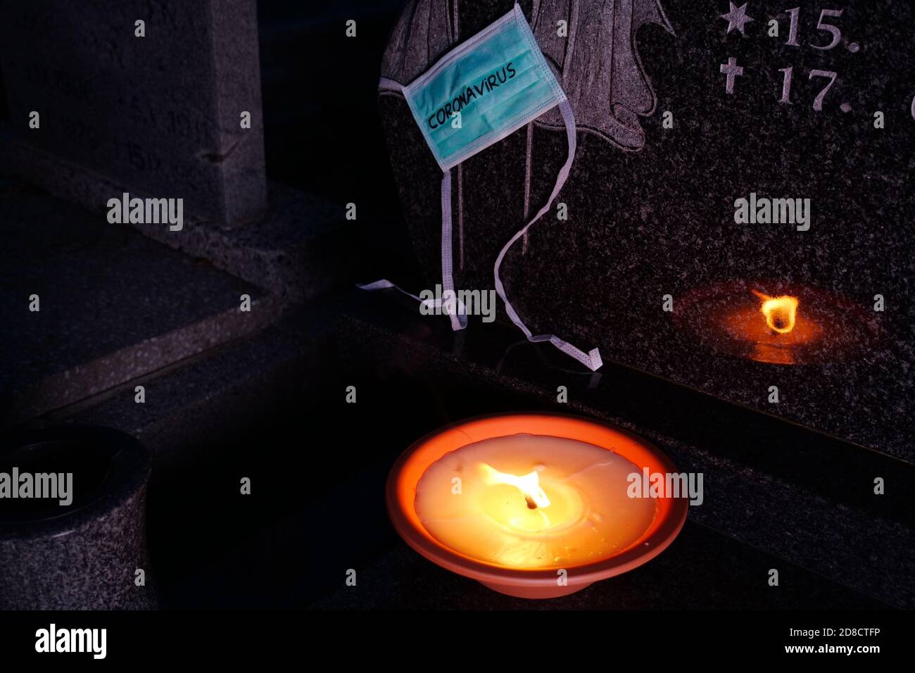 Concept d'éclosion de coronavirus. Décès causé par le coronavirus, victime du virus Covid-19. Lumière de bougie et masque médical à la tombe dans le cimetière. Banque D'Images