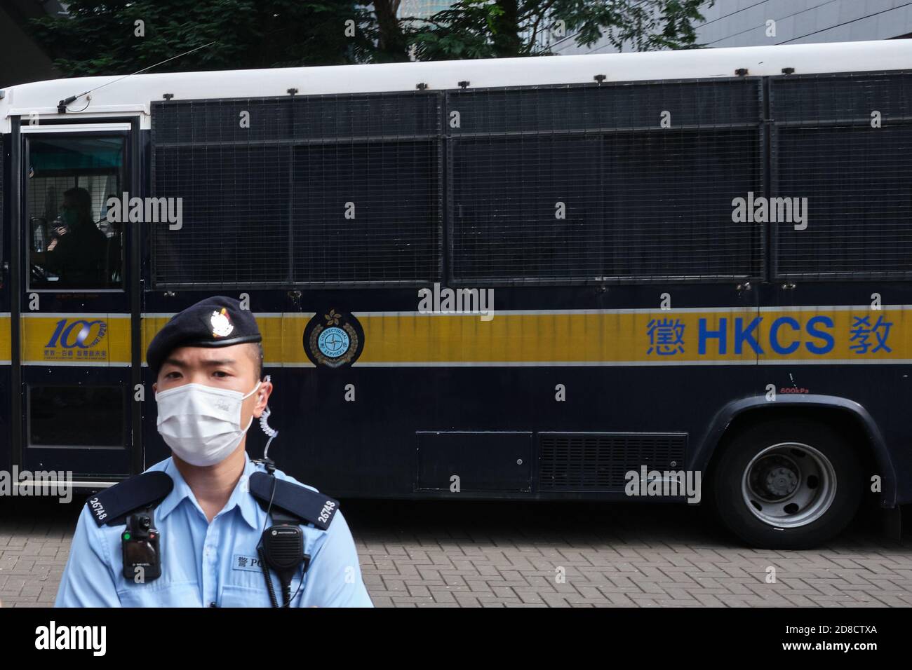 Un policier portant un masque est vu devant une fourgonnette des services correctionnels transportant le militant de Hong Kong Tony Chung, 19 ans, accusé de sécession en vertu de la nouvelle loi sur la sécurité nationale, après avoir été privé de caution de la Cour des magistrats de West Kowloon. Banque D'Images