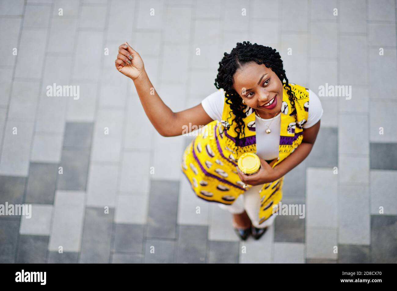 Vue d'en haut de l'élégant afro-américain femmes en blouson jaune posé dans  la rue avec boisson chaude dans gobelet en papier jetable Photo Stock -  Alamy