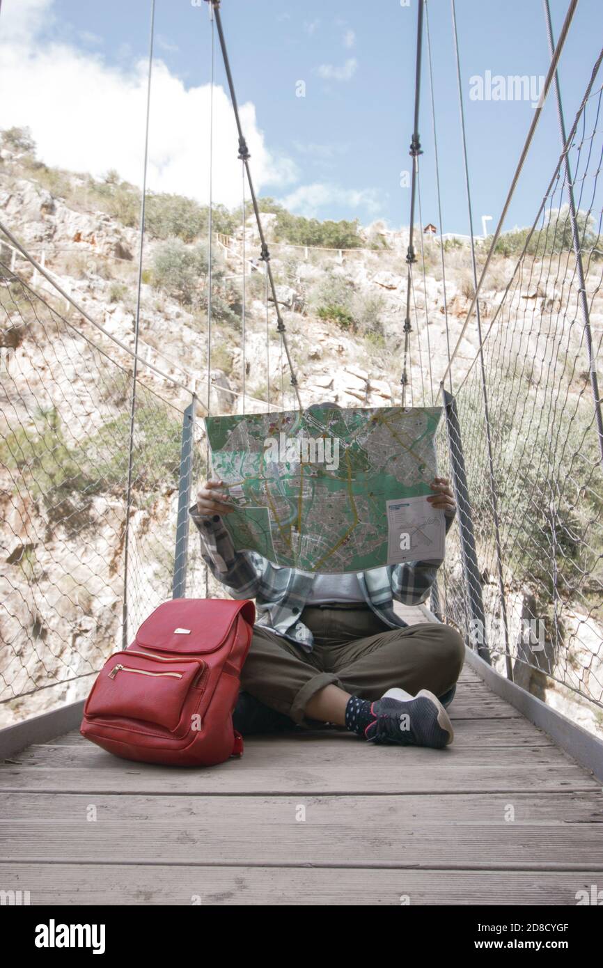 Backpacker fille assise sur un pont suspendu à Chulilla, regardant sa carte pour localiser la région. Activités de randonnée. Activités de plein air. Photo de voyage. Banque D'Images