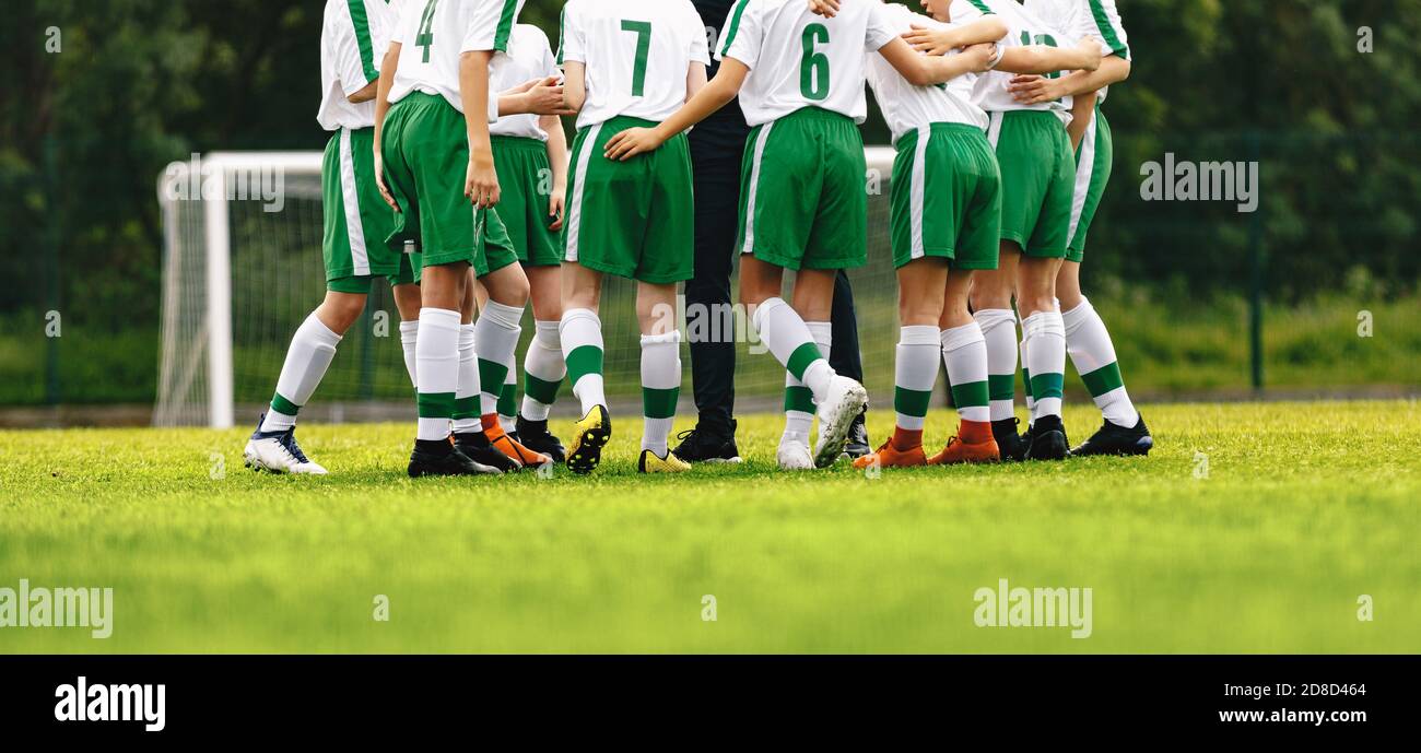 Adolescents en équipe sportive avec entraîneur. Briefing de football avec l'entraîneur. Garçons en uniforme avec chiffres au dos. L'entraîneur motive les joueurs de football juniors befor Banque D'Images