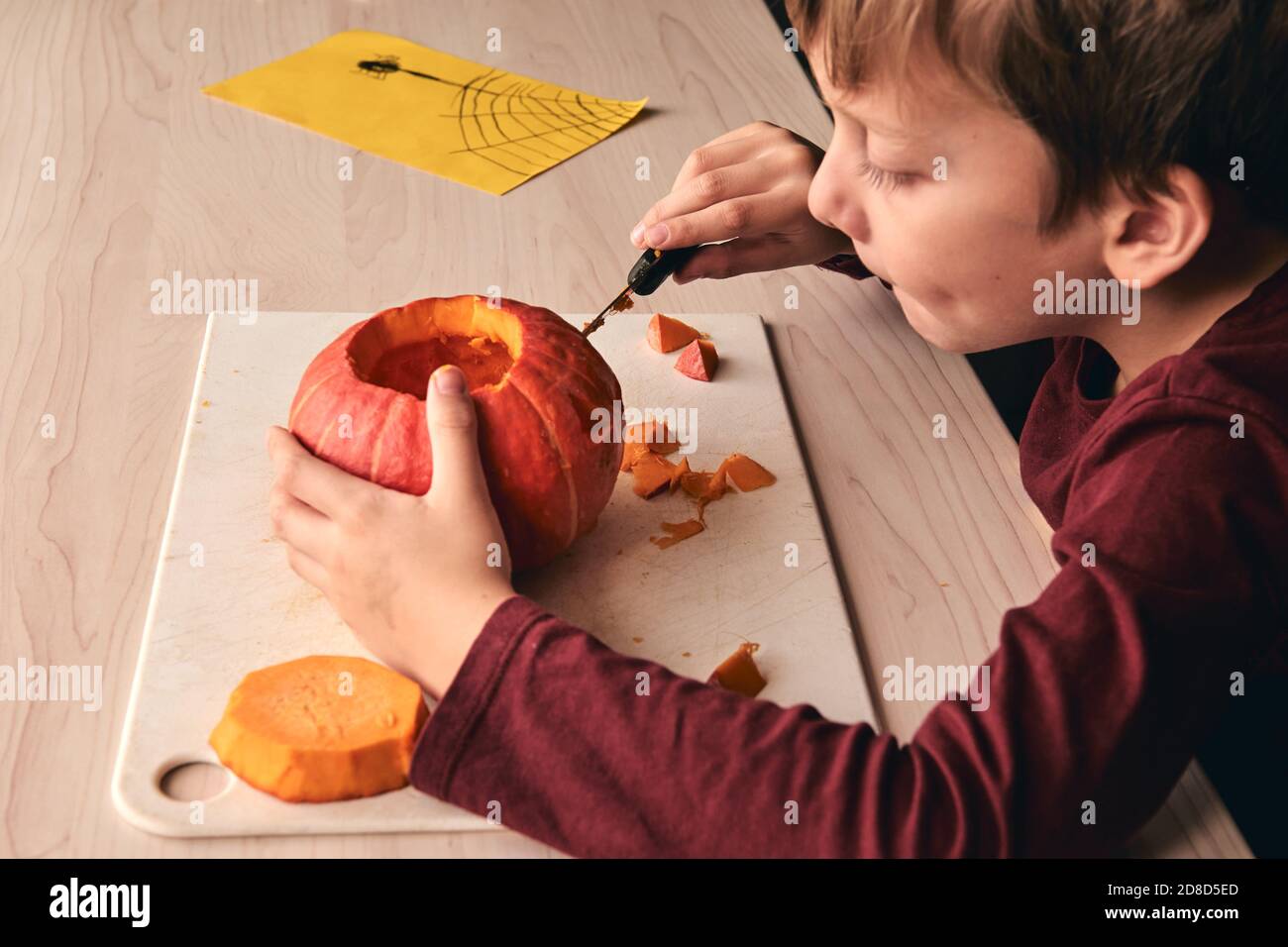 Halloween, décoration et idées de vacances - gros plan de l'enfant avec couteau sculptant la citrouille ou la citrouille-o-lanterne. 6 ans, garçon a une activité amusante à domicile. Maman Banque D'Images