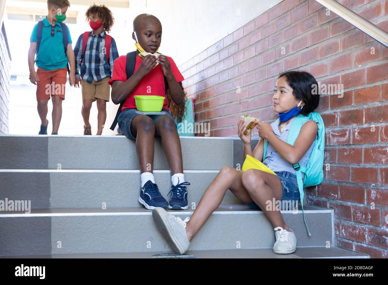 Un garçon et une fille mangent un déjeuner dans une boîte de tiffin tout en étant assis dans les escaliers de l'école Banque D'Images