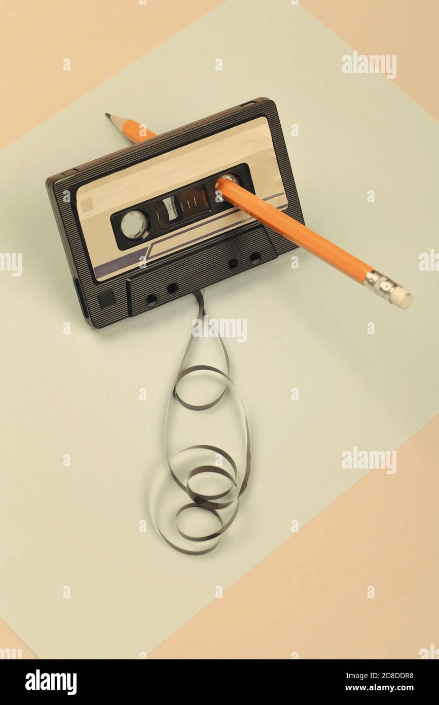 cassette audio avec ruban enchevêtrement sur fond bleu et beige avec crayon  jaune, composition minimaliste. concept rétro Photo Stock - Alamy