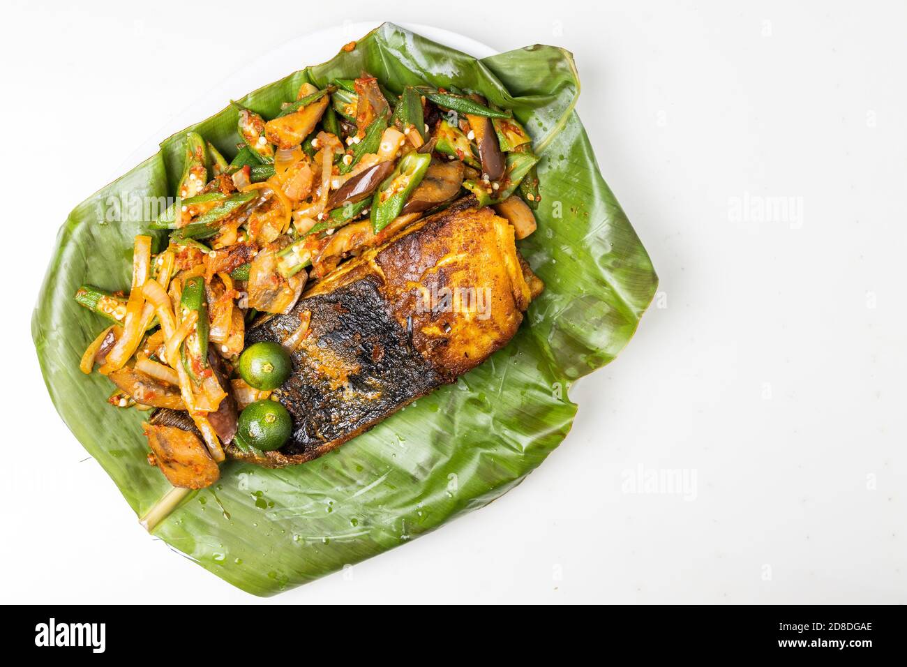 Vue en hauteur sur les populaires poissons à raies grillées aux épices et légumes servis sur feuille de banane Banque D'Images