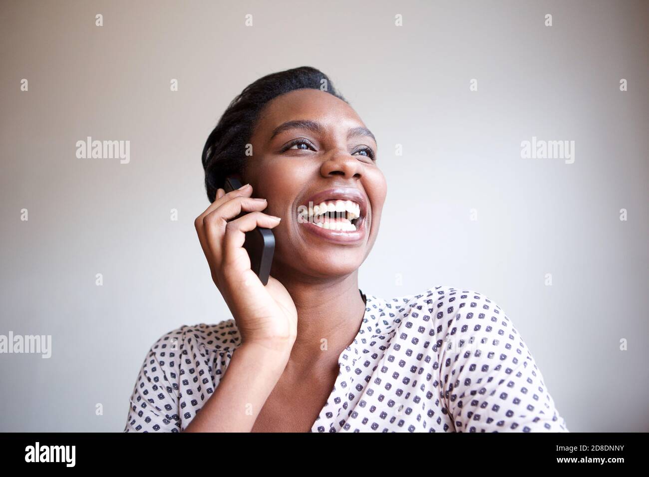 Portrait en gros plan d'une femme noire heureuse qui rit au téléphone conversation Banque D'Images