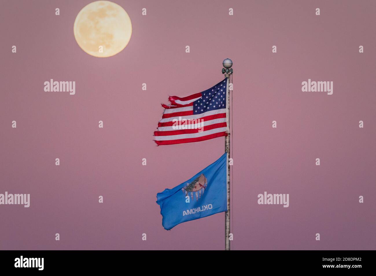 Une belle pleine lune qui monte sur le drapeau américain et de l'Oklahoma alors que le soleil se couche. Banque D'Images