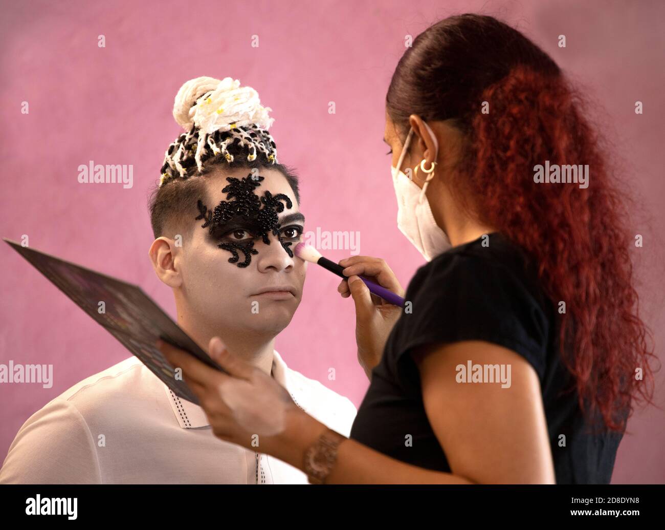 Maquilleuse avec un masque pour peindre le visage d'un homme halloween Banque D'Images