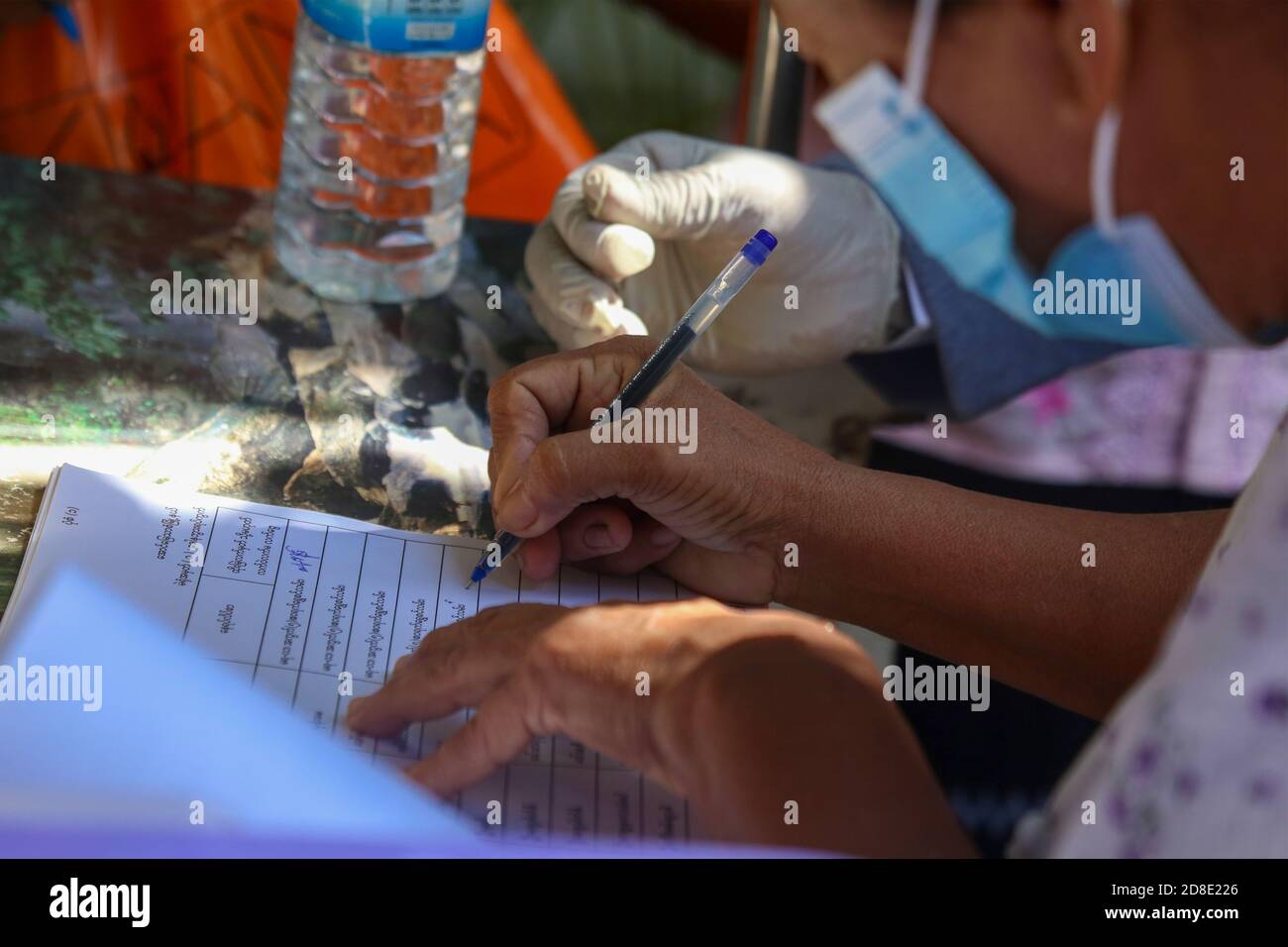 Une vieille femme portant un masque facial signe le livre des records avant de voter.la commission électorale de l'Union fait le vote par anticipation pour les personnes âgées de plus de (60) ans. Les électeurs de plus de (60) ans du canton de Mandalay, Aung Myay Thar Zan, pourront voter à l'avance le matin du 29 octobre. Les élections générales du Myanmar auront lieu le 8 novembre. Banque D'Images