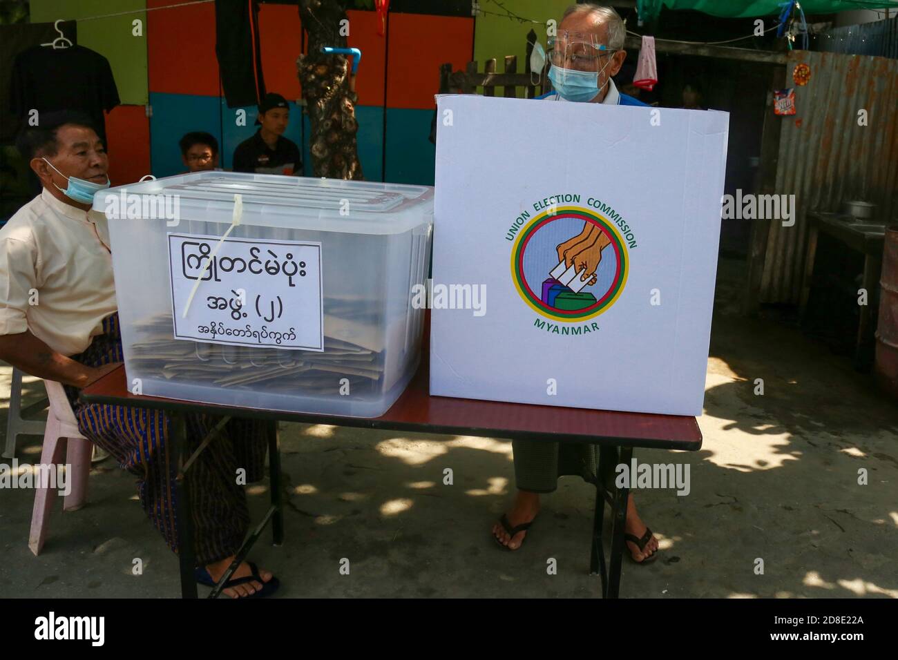 Un homme âgé portant un masque facial et un écran facial lance son bulletin de vote à un poste de vote.la commission électorale de l'Union vote à l'avance pour les personnes âgées de plus de (60) ans. Les électeurs de plus de (60) ans du canton de Mandalay, Aung Myay Thar Zan, pourront voter à l'avance le matin du 29 octobre. Les élections générales du Myanmar auront lieu le 8 novembre. Banque D'Images