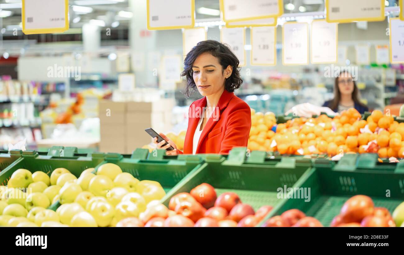 Au supermarché: Belle femme choisit les fruits biologiques dans la section des produits frais du marché agricole. Elle choisit des fruits et tient Banque D'Images