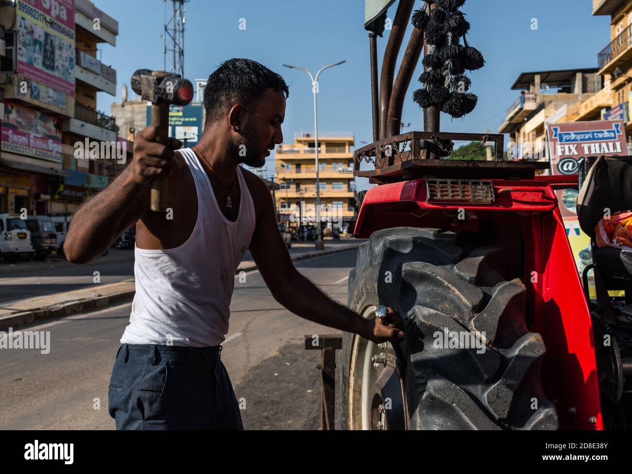 Jaisalmer, Rajasthan / Inde - septembre 28 2020 : mécanicien remplaçant le pneu de tracteur par un marteau dans un centre d'entretien automobile Banque D'Images