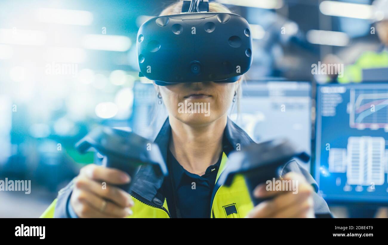 Portrait Femme Ingénieur en mécanique portant un casque de réalité virtuelle et utilisant des contrôleurs, elle utilise la technologie VR pour la conception industrielle, le développement Banque D'Images